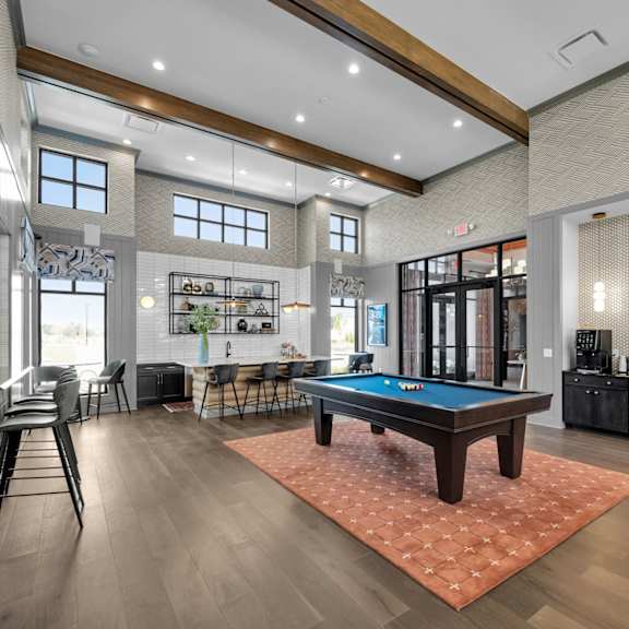 a room with a pool table and a bar area.