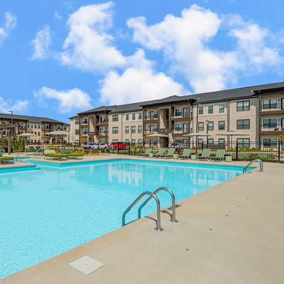 a swimming pool with an apartment building in the background