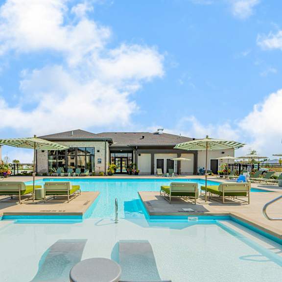 a swimming pool with lounge chairs and a building in the background