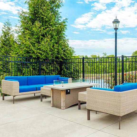 a patio with couches and a table in front of a fence