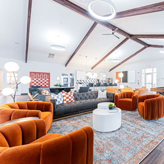 a living room with orange chairs and a black couch.