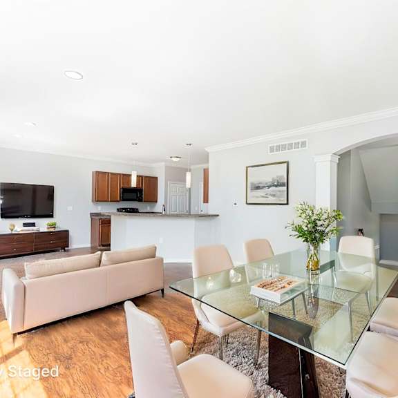 a modern living room with a glass table and white chairs.