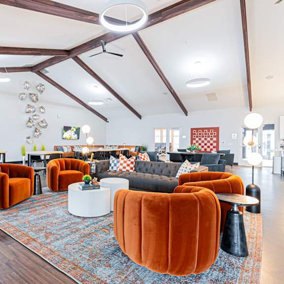 a living room with orange chairs and a grey couch.