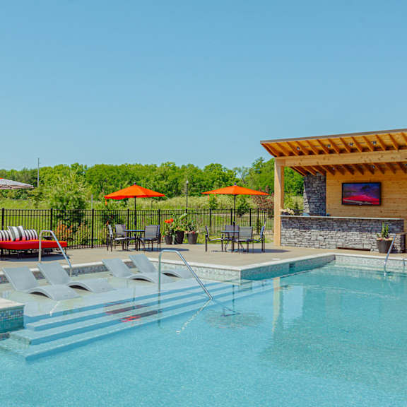 a swimming pool with chairs and umbrellas next to a resort style pool