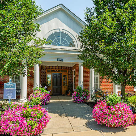 the front of a brick building with flowers and trees