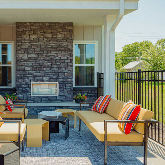 a patio with furniture and a fireplace on the side of a house