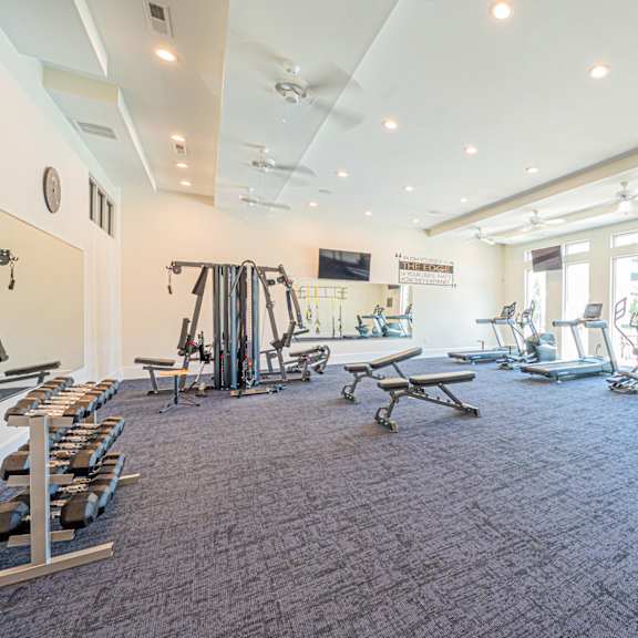 a gym with weights and cardio equipment in a building with windows
