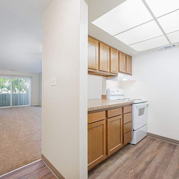 an empty kitchen and living room with wood flooring and a window