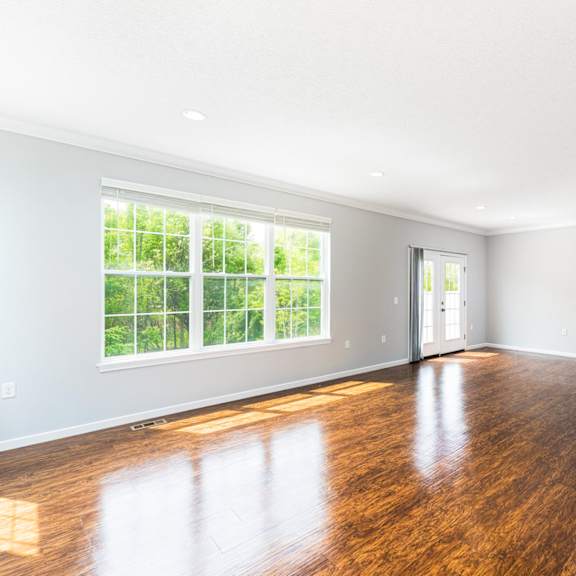 a spacious kitchen and living room with wooden floors and white walls.