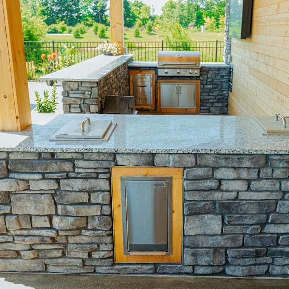 a stone bar with a grill on the side of a house