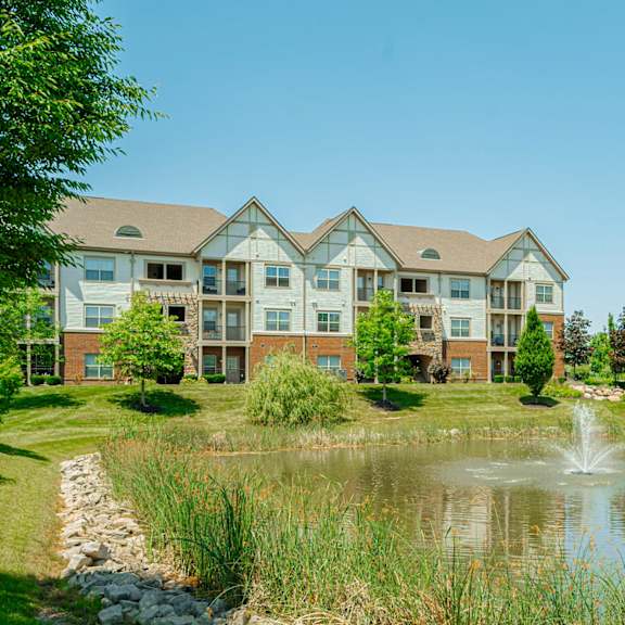 a pond with a fountain in front of an apartment building