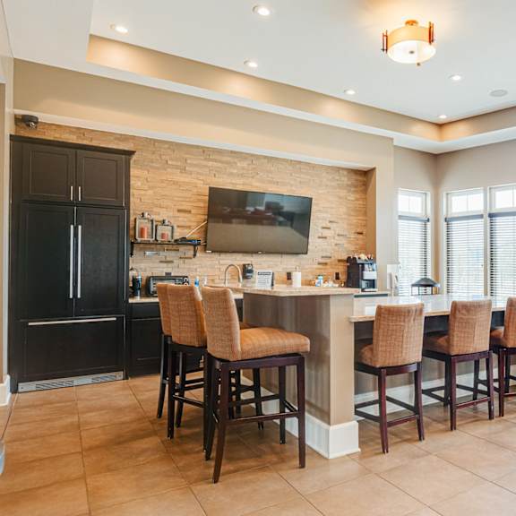 a kitchen with a bar with chairs and a television