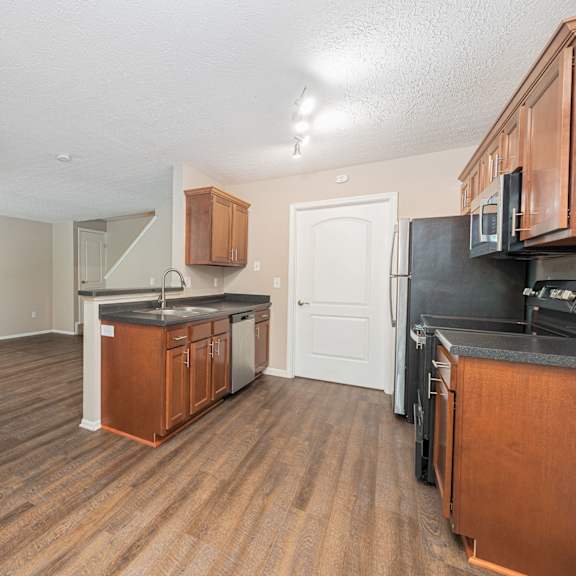 an empty kitchen with wood flooring and black appliances