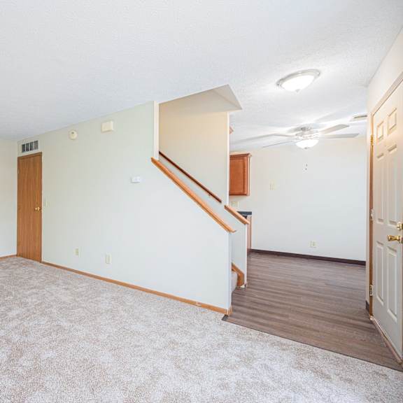 a living room with carpet and a door to a staircase