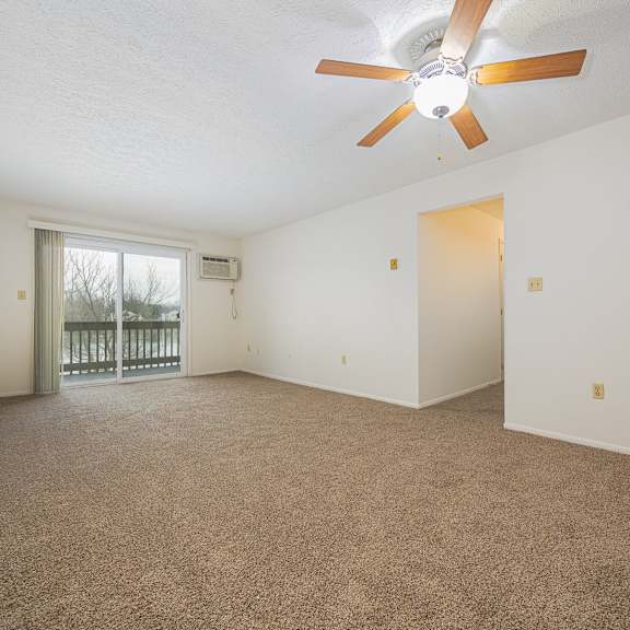a room with a ceiling fan and carpeted floor.
