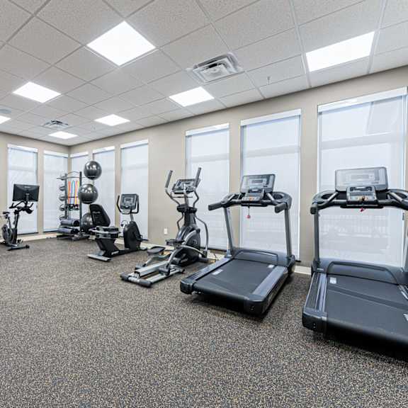 a spacious gym with a variety of equipment including treadmills, elliptical machines, and weight machines.