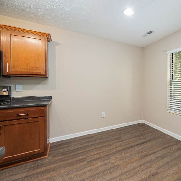 an empty living room with a window and a kitchen