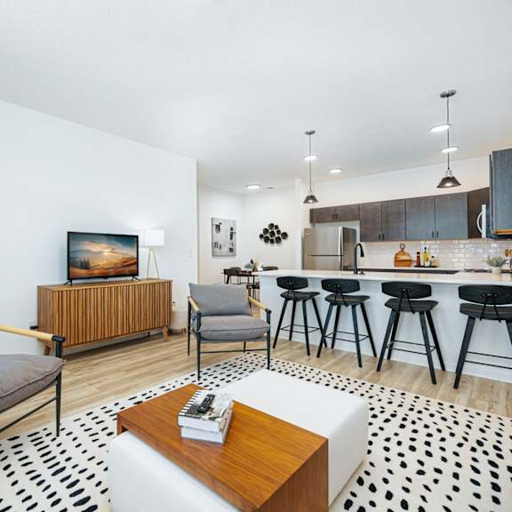 a living room with a kitchen and a bar with stools