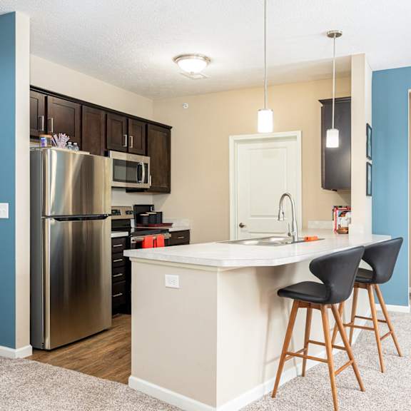 a kitchen with a island and a stainless steel refrigerator