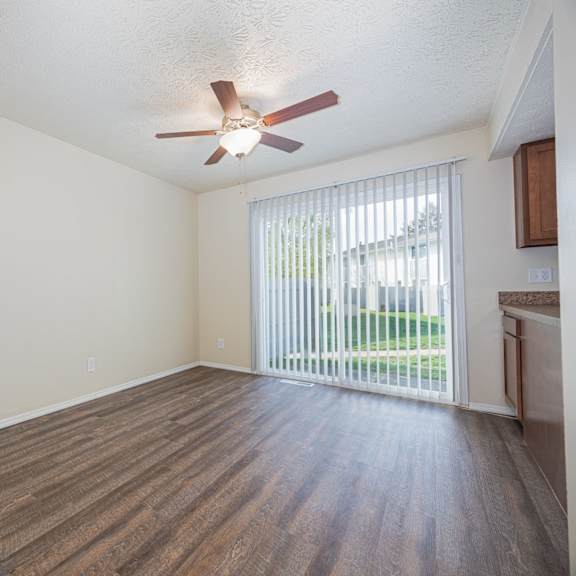 a room with a ceiling fan and sliding glass doors.