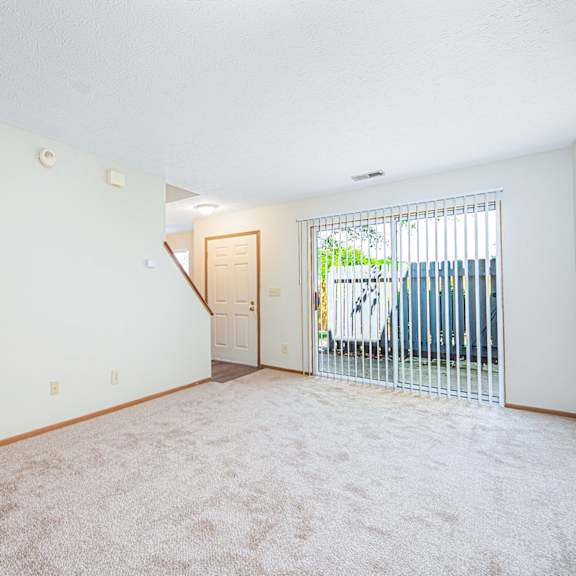 an empty living room with a door to a balcony