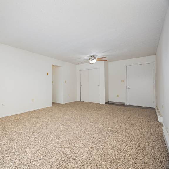 a room with carpeted floor and a ceiling fan.