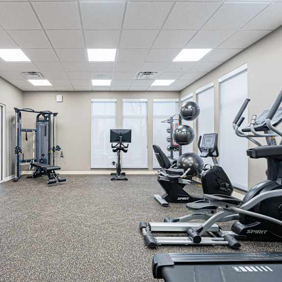 a spartan room with a treadmill, weights and exercise equipment.
