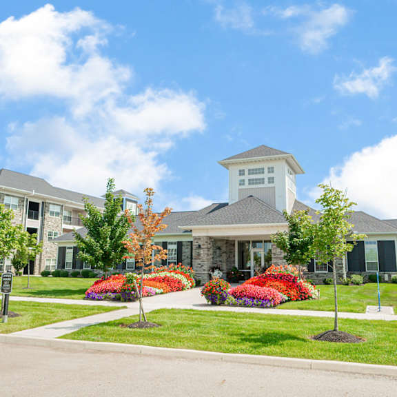 an exterior view of an apartment building with a lawn and flowers