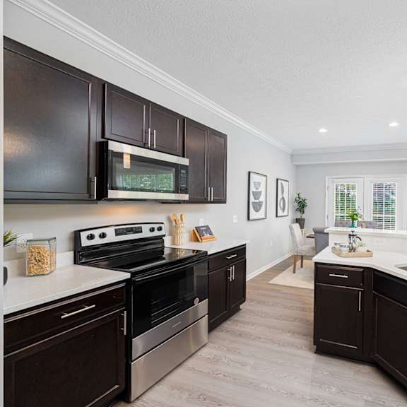 a large kitchen with black cabinets and white counter tops and a sink