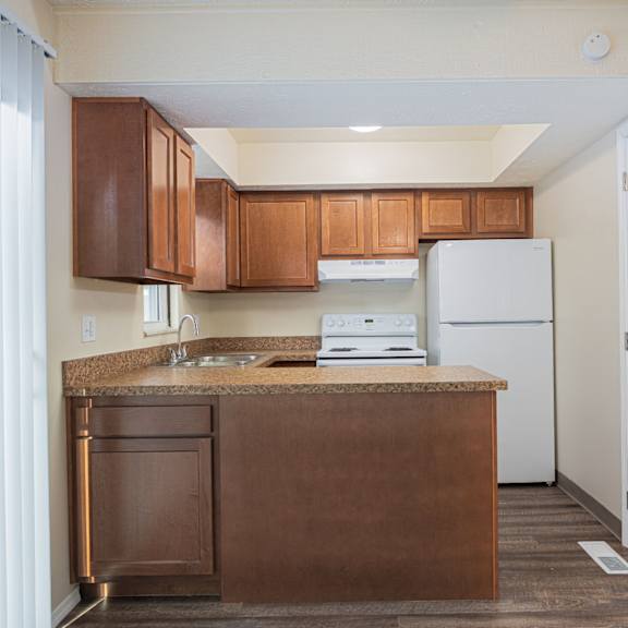 a kitchen with brown cabinets and a white refrigerator.