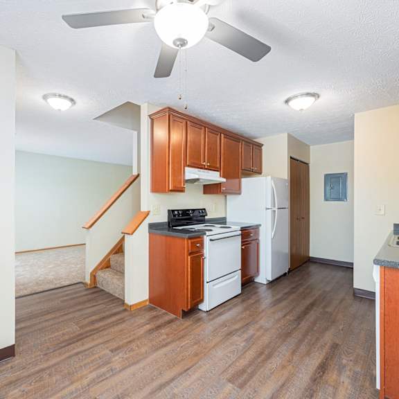 an empty kitchen with a ceiling fan and a staircase