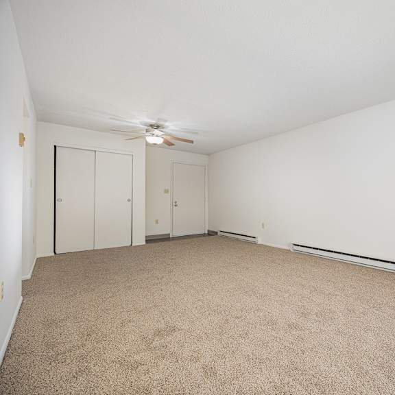 a room with a carpet floor and a ceiling fan.