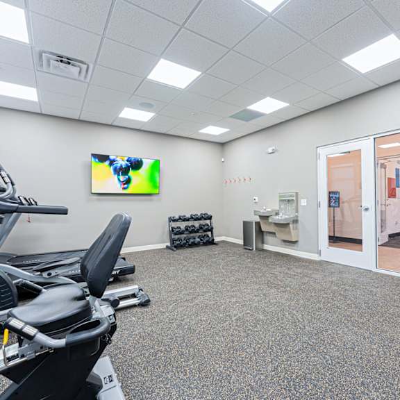 a gym room with treadmills and a television.