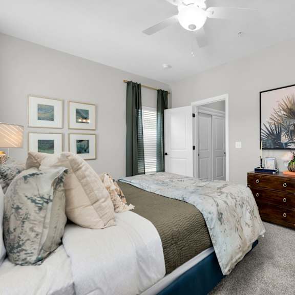 a bedroom with a bed, dresser, and a ceiling fan.