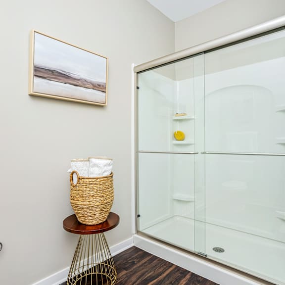 a bathroom with a glass shower and a basket next to it