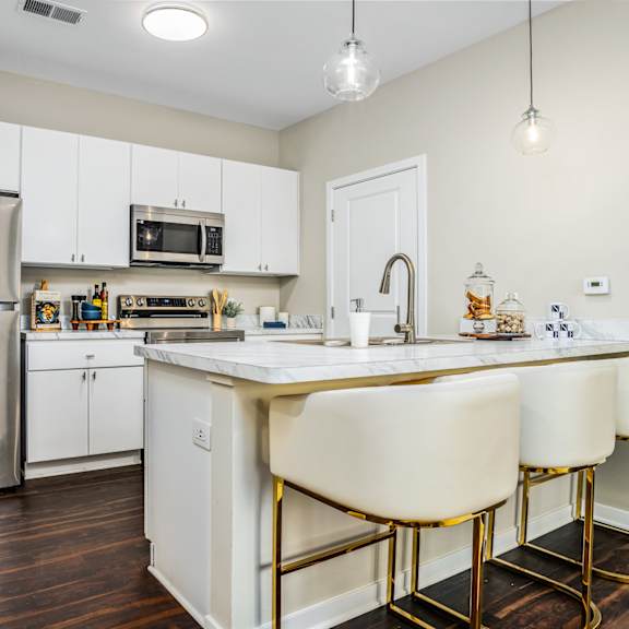 a kitchen with white cabinets and a counter top and a stainless steel refrigerator