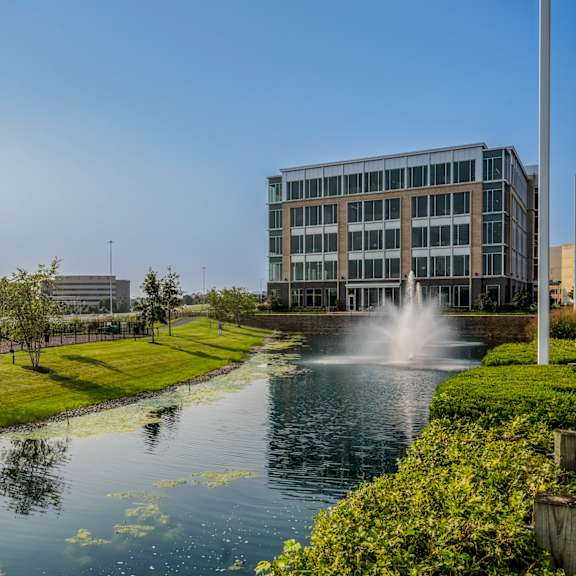 a pond with a fountain in front of a building