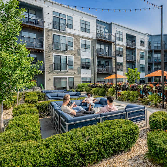 people sitting on a couch in an outdoor courtyard at an apartment building