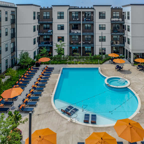 an aerial view of an apartment pool with umbrellas and lounge chairs around it