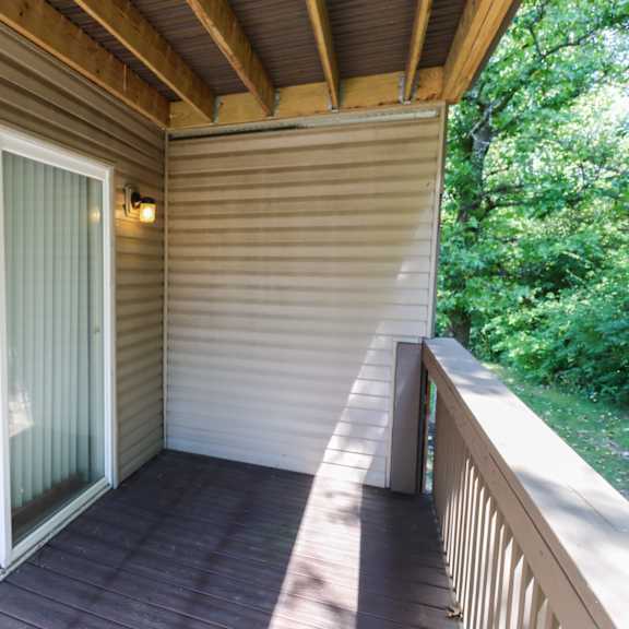 a covered porch with sliding glass doors and a wooden deck