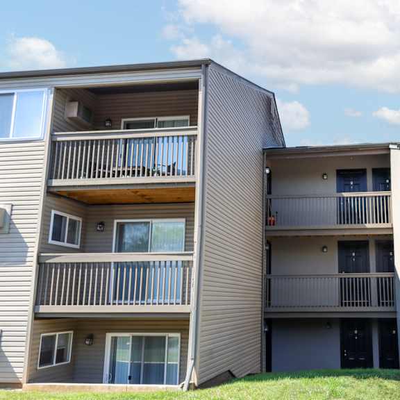 a view of two apartment buildings with balconies and a lawn