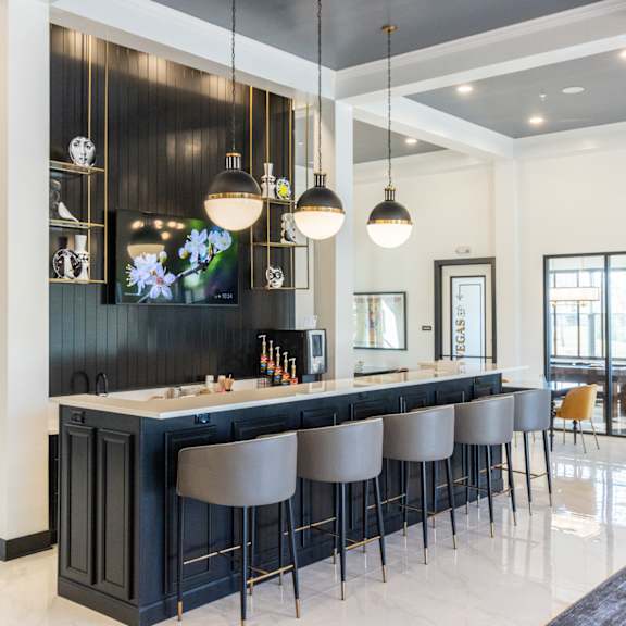 a bar with bar stools in a living room with a dining table and chairs