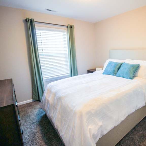 a bedroom with white bedding and green pillows