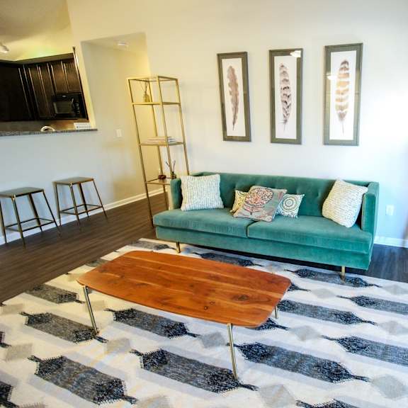 a living room with a green couch and a cowhide rug