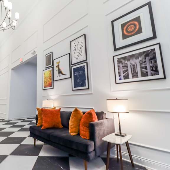 a lobby with a black and white checkered floor and a couch with orange pillows