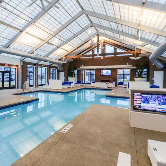 a large indoor pool with a skylight and televisions