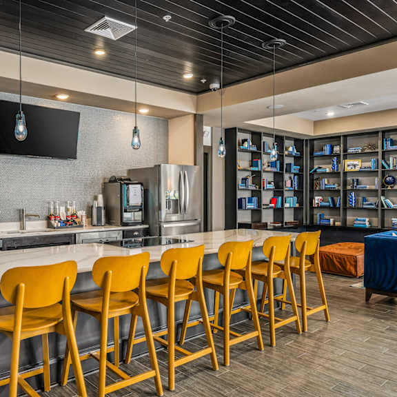 a kitchen with a bar and yellow chairs