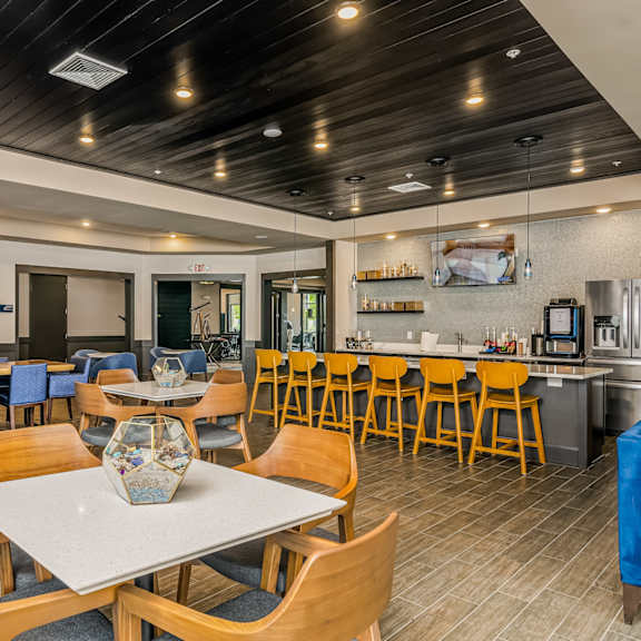 a dining area with tables and chairs and a kitchen in the background