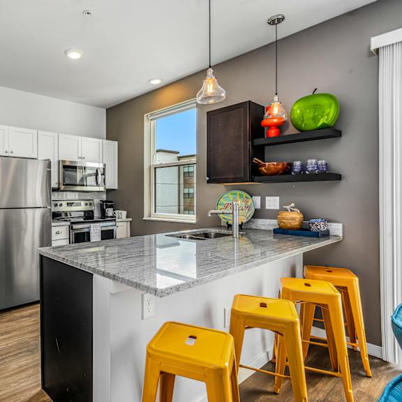 a kitchen with a counter with bar stools and a stainless steel refrigerator
