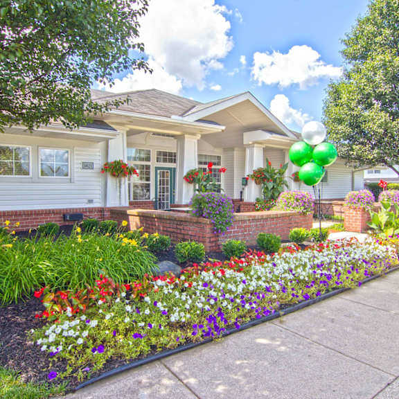 the front yard of a house with flowers and a sidewalk